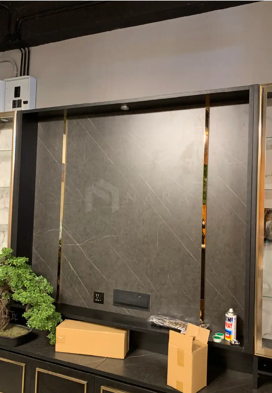 Polished gold stainless steel trim accents on dark marble wall for elegant interior design.