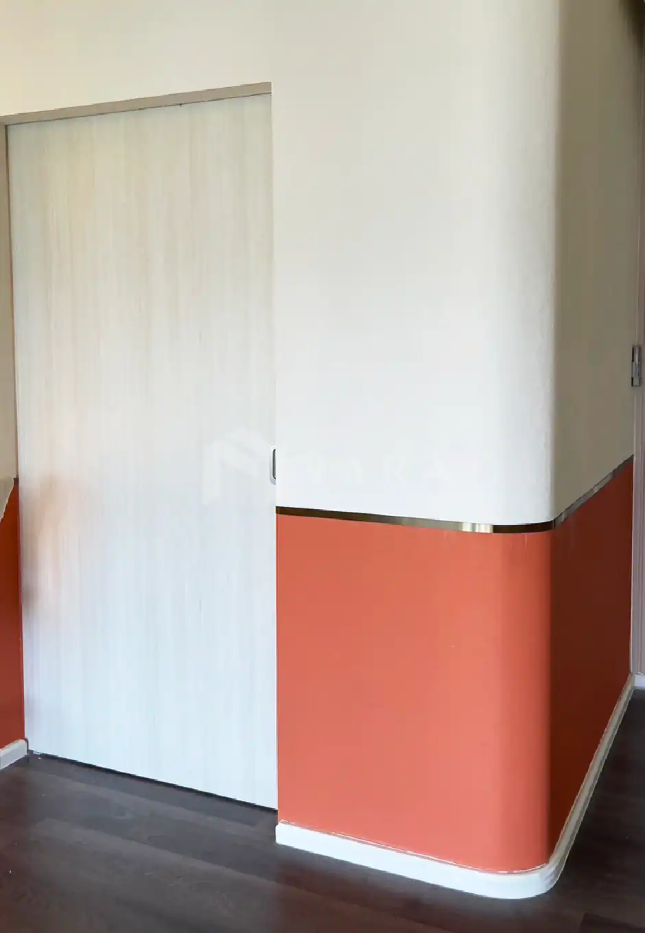 Shiny gold-colored stainless steel trim and corner accents on a modern interior wall with a sliding door, featuring sleek design and durable materials for stylish interior decoration.
