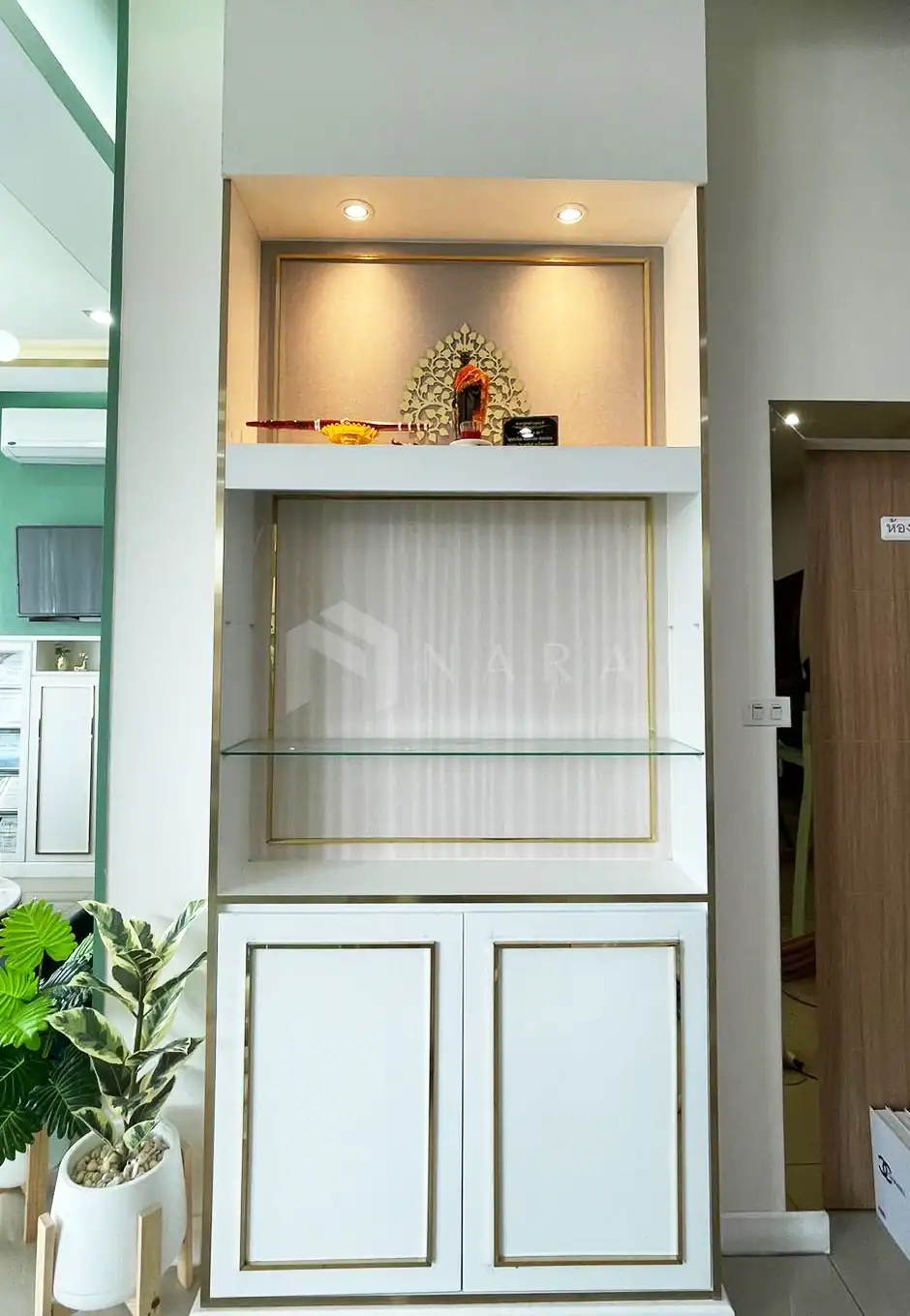 Shiny gold stainless steel decorative trim on a white display cabinet with lighting, ideal for interior design or furniture accents.