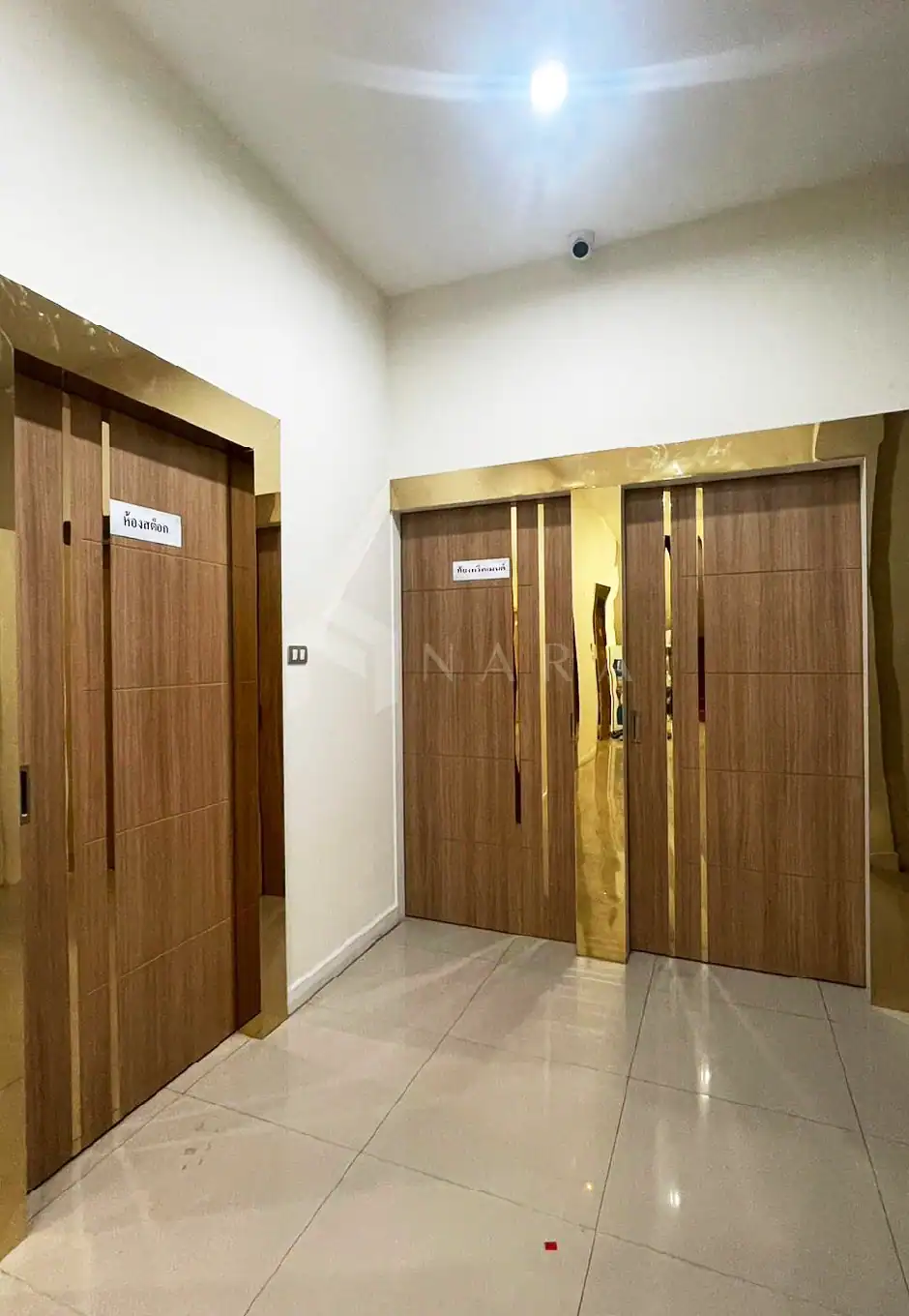 Shiny gold stainless steel door frames with wood panels, elegant interior design, modern decorative accents, NARA Stainless gold-colored stainless steel trim, upscale building interior enhancements, luxury architectural details.