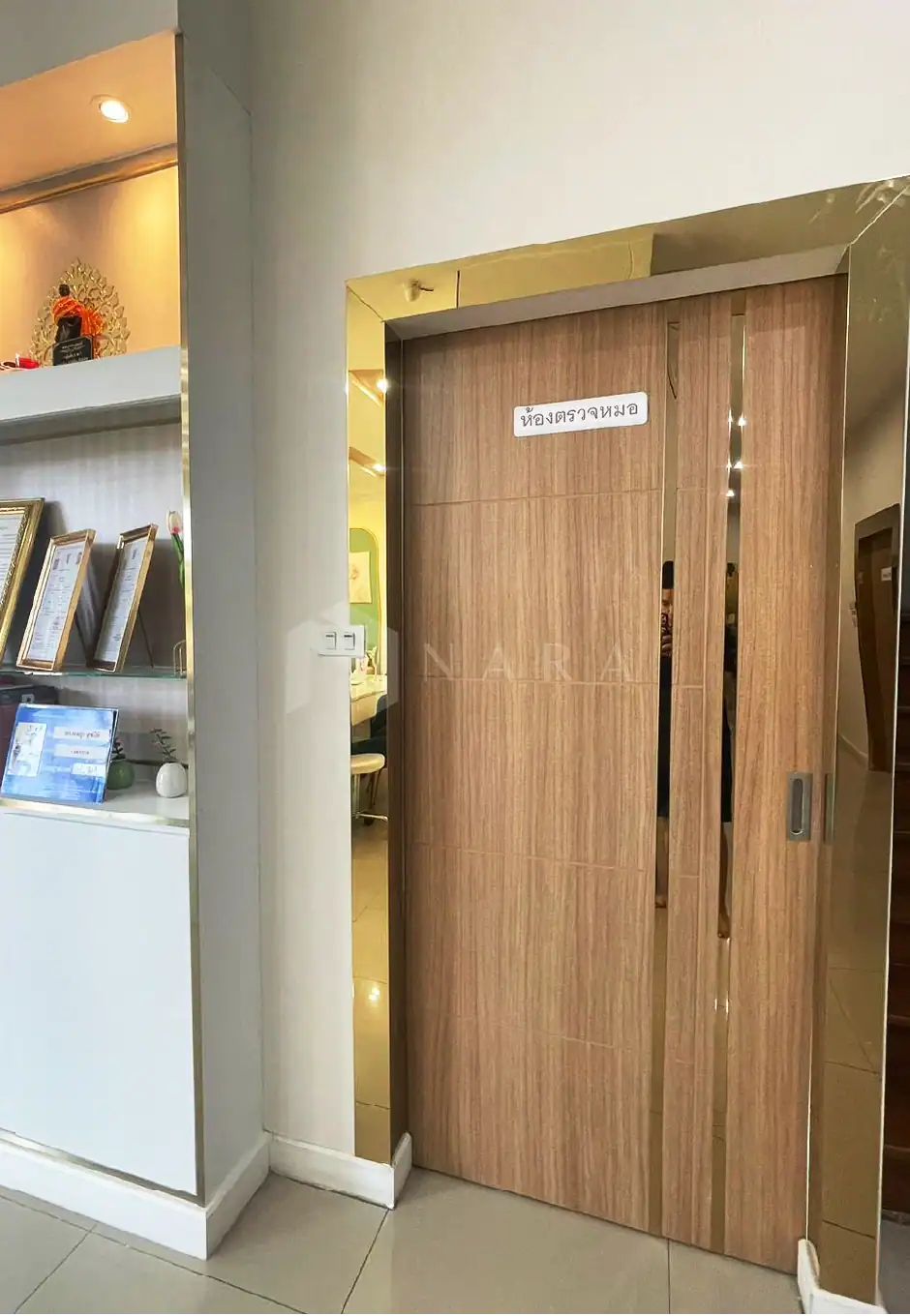 Shiny wooden sliding door with gold stainless steel frame, used as an interior partition in a modern office or clinic setting. The door features a sleek design and practical sliding mechanism.