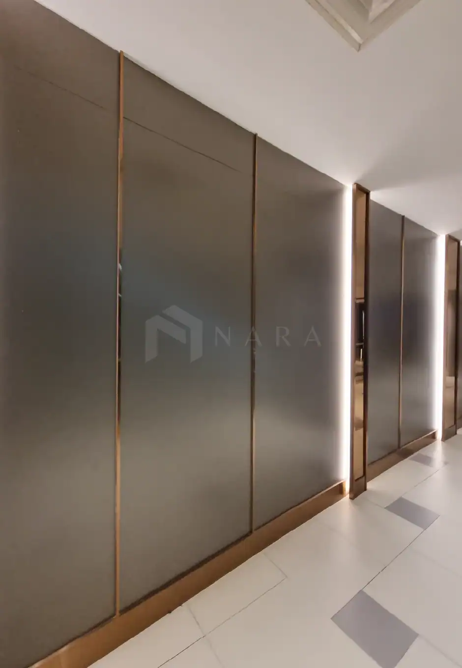 Shiny gold stainless steel corner trim panels with LED lighting accents in a modern interior space.