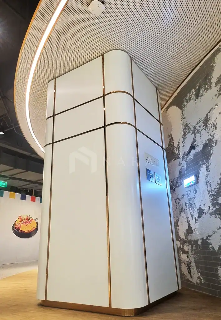 Sleek white panel with gold accent strips on a modern interior wall, featuring integrated electrical outlets and sleek design elements, creating an elegant contemporary look in a commercial space.