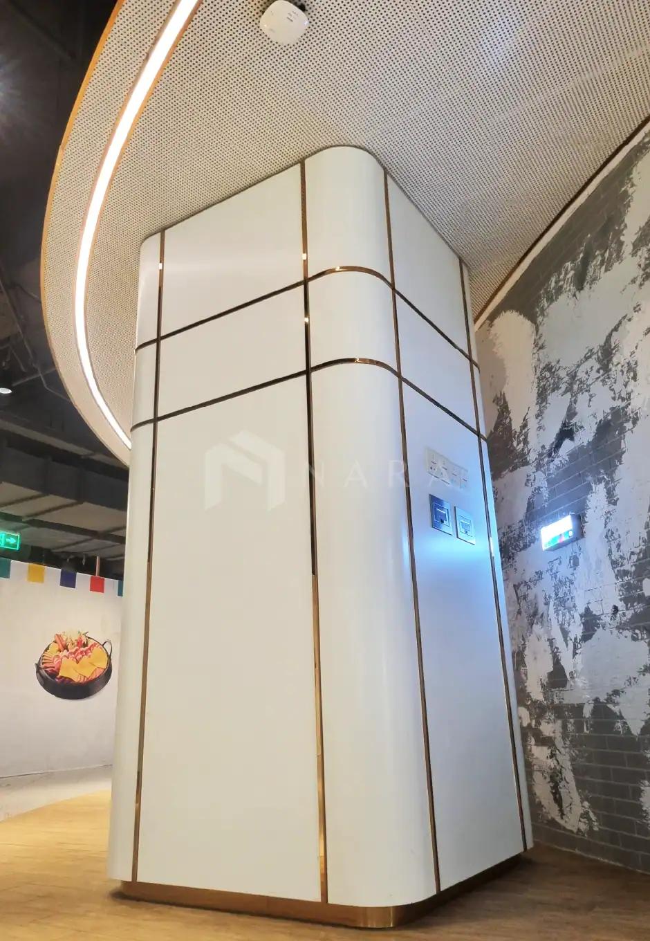 Sleek white panel with gold accent strips on a modern interior wall, featuring integrated electrical outlets and sleek design elements, creating an elegant contemporary look in a commercial space.