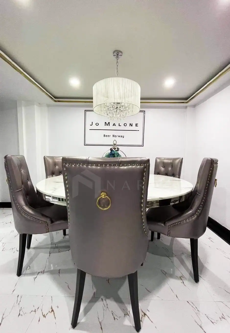 Luxurious gold stainless steel corner trim and decorative accessories in a modern dining room setting with elegant chairs and chandelier for upscale interior decor.