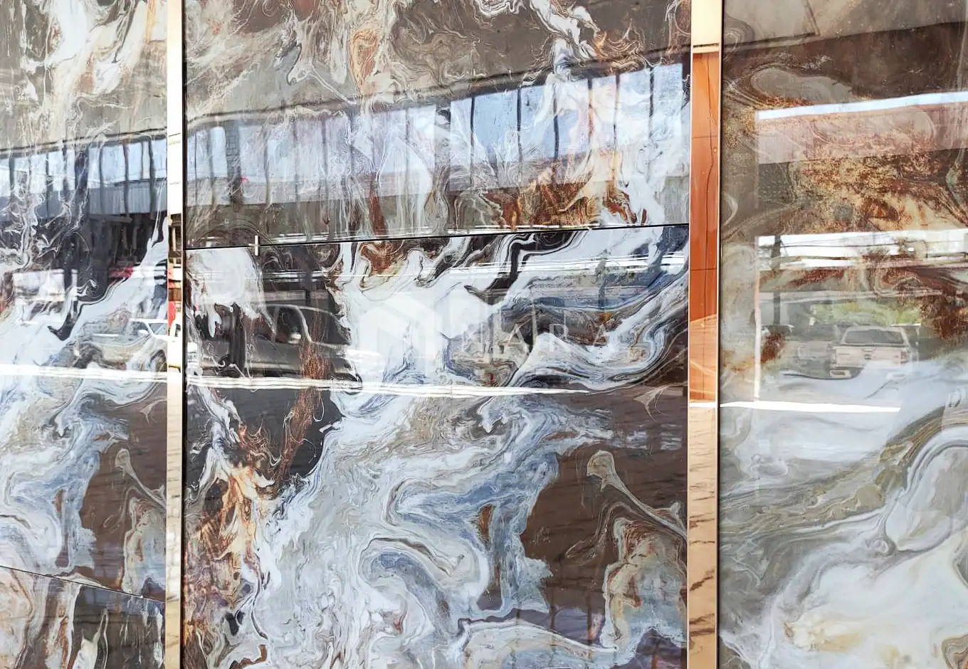 Shiny gold-colored stainless steel decorative trims and accents on a marble wall for luxurious interior design.