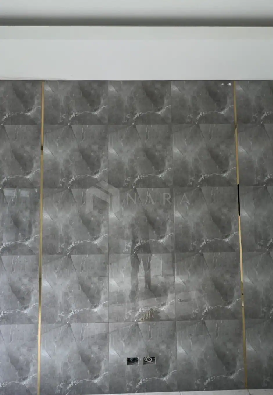 Glossy grey marble wall tiles with gold-colored stainless steel trim, creating a luxurious and elegant interior design accent. Perfect for upscale commercial or residential spaces seeking modern sophistication.